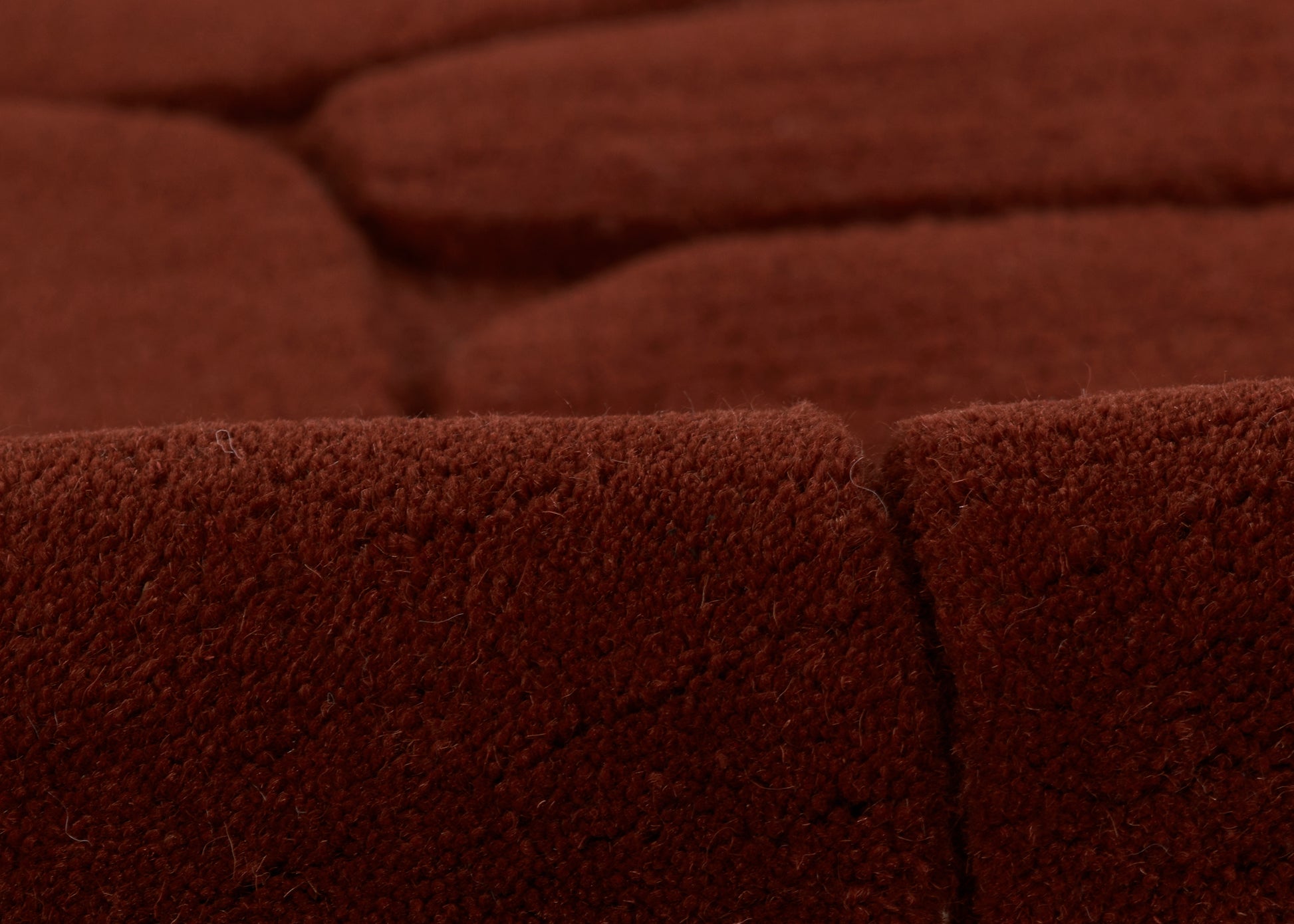 Deep burgundy velvet rug close-up with seam, plush textured pile.