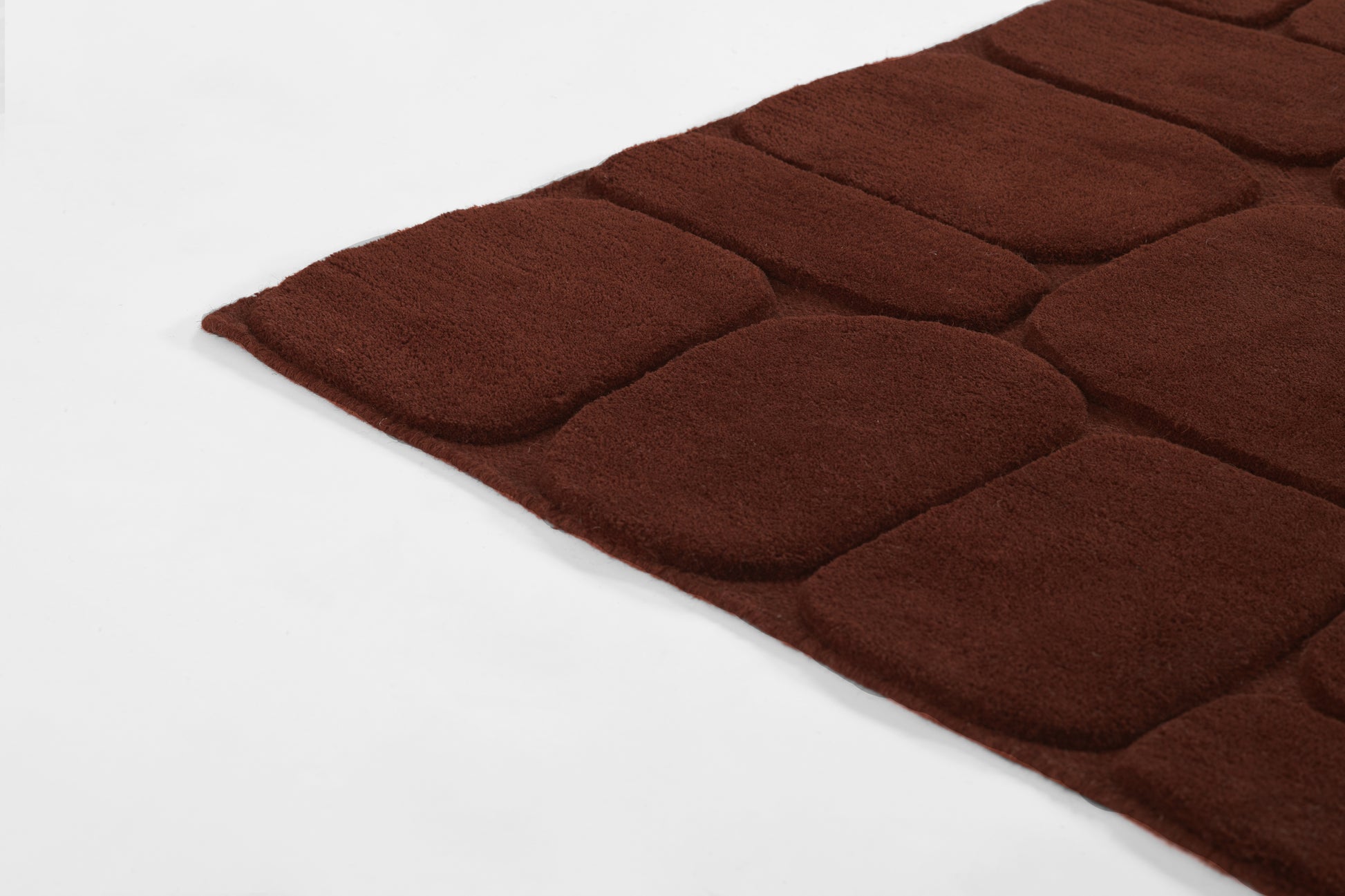 Maroon tufted rug with rounded rectangular blocks; plush shag texture, ideal as an area or bathroom rug.
