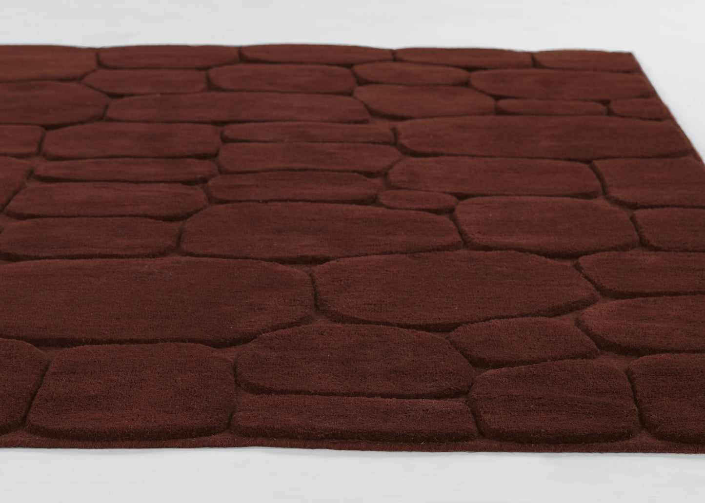 Dark rust-brown plush area rug with rounded stone-tile pattern and soft shag texture