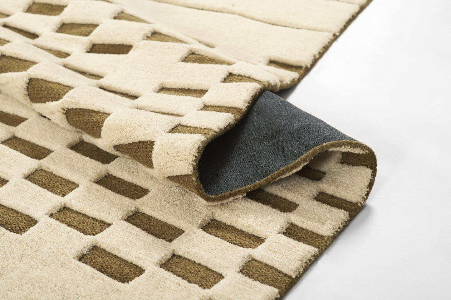 Beige and brown geometric lattice rug with plush pile; rolled corner reveals dark gray backing.
