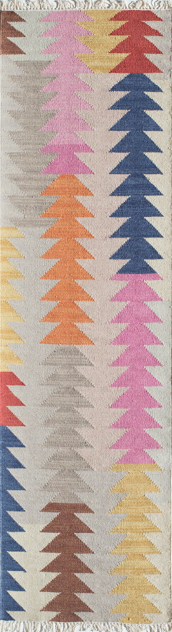 Long narrow woven rug with columns of colored triangular trees; pink, orange, yellow, blue, red on beige with fringed ends.