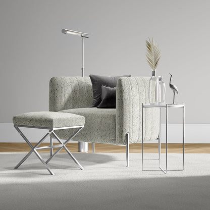 Light textured gray-green armchair with matching ottoman and chrome legs, paired with glass side tables and modern decor.