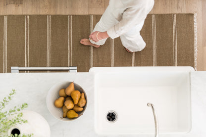 Top-down view of a brown striped rug runner on the floor.