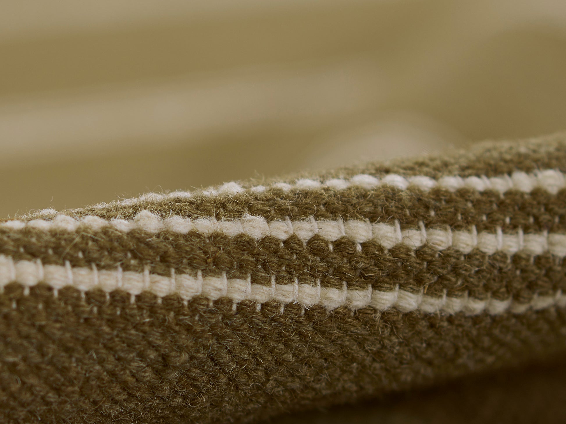 Close-up of brown and cream striped woven rug edge with chunky yarn texture.