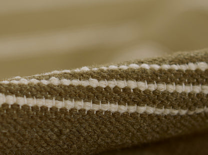 Close-up of brown and cream striped woven rug edge with chunky yarn texture.