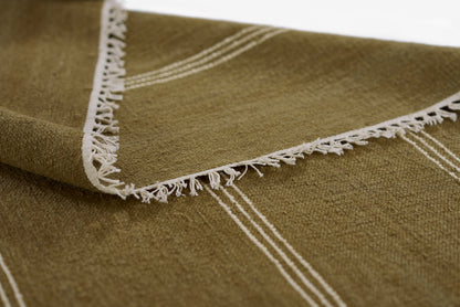 Olive green woven rug with cream fringe along the edge and subtle white stripes.