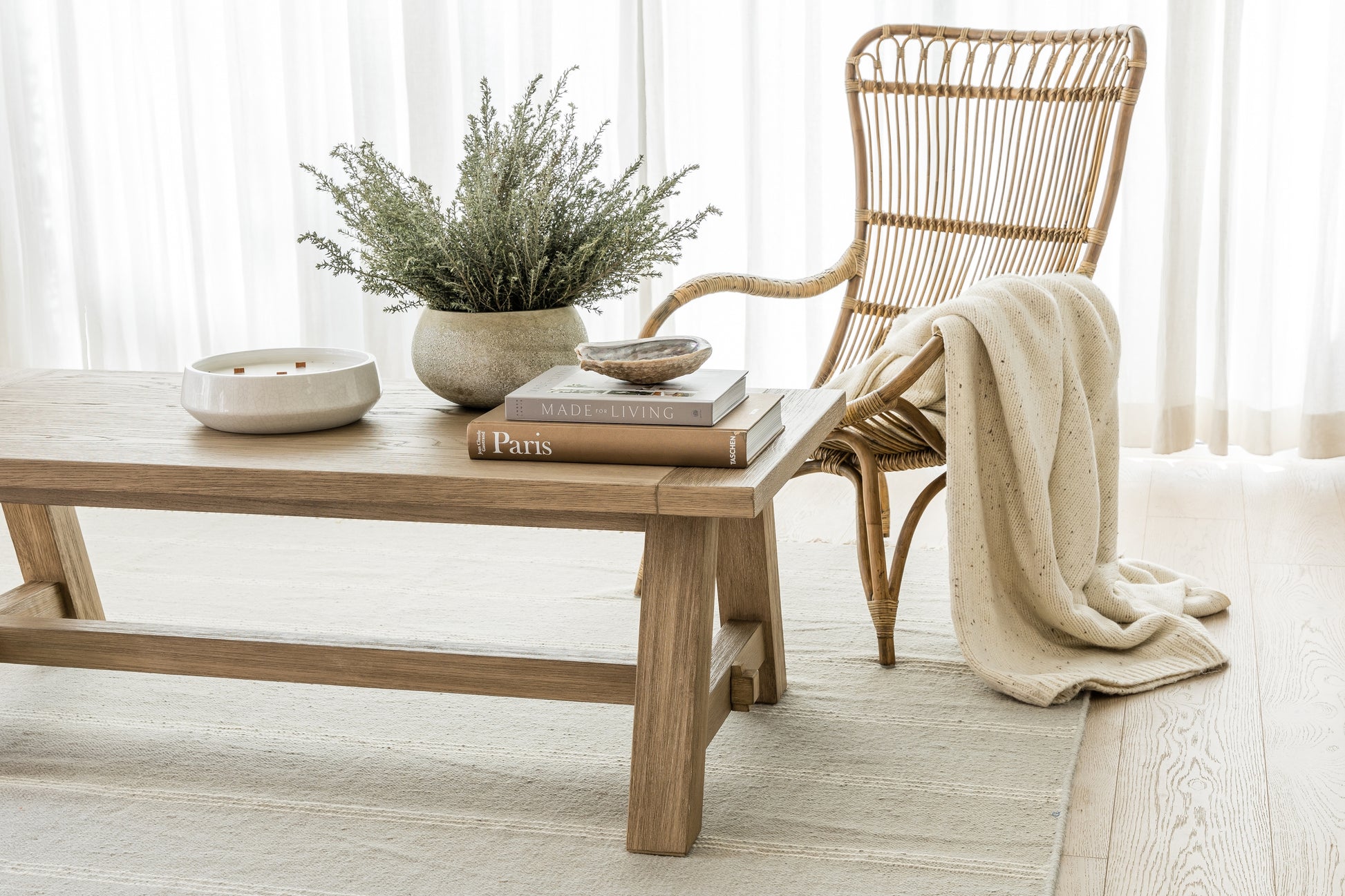 3' x 8' rug runner on a beige floor in a living room, with a natural wood coffee table holding greenery, books and a ceramic bowl, plus a wicker rattan chair and a cream throw.