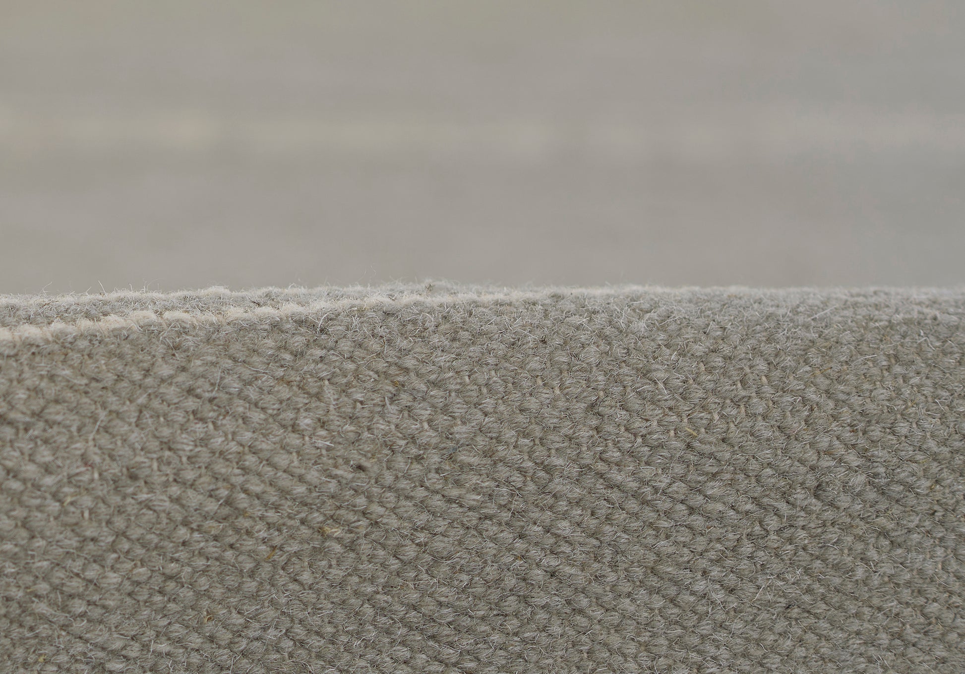 Close-up of gray loop-pile carpet edge, textured wool-like upholstery fabric, neutral-modern style.
