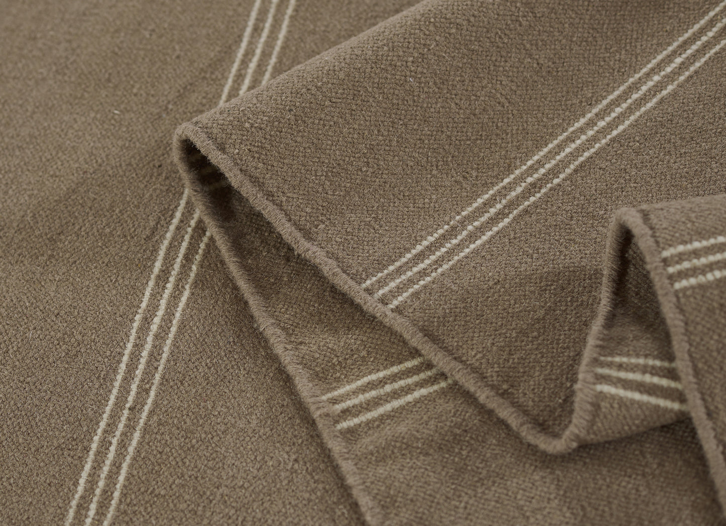 Brown taupe rug runner (3' x 8') with white double stripes along the edge, plush pile, folded.