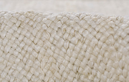 Close-up of cream braided jute weave; thick, chunky fibers create a natural rustic texture for baskets or bags.