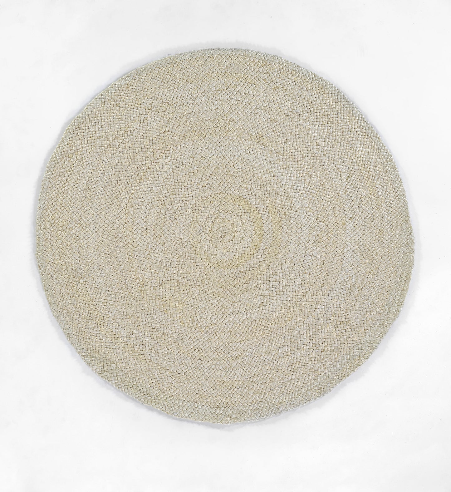 Beige natural jute rug with tight circular woven texture, flat-weave, artisanal coastal style.