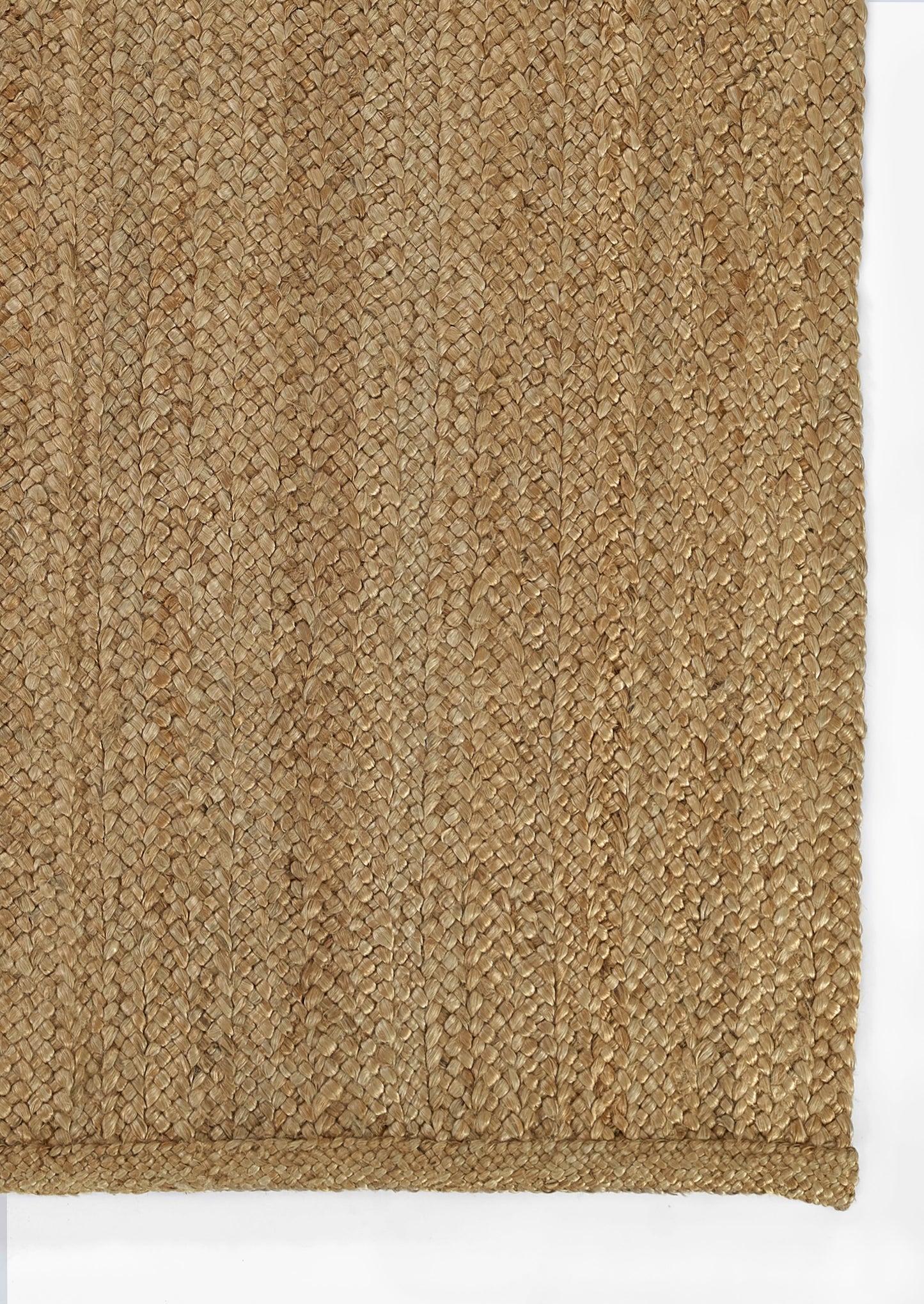 Natural jute rug close-up showing a tan braided weave and bound edge, rustic coastal style.