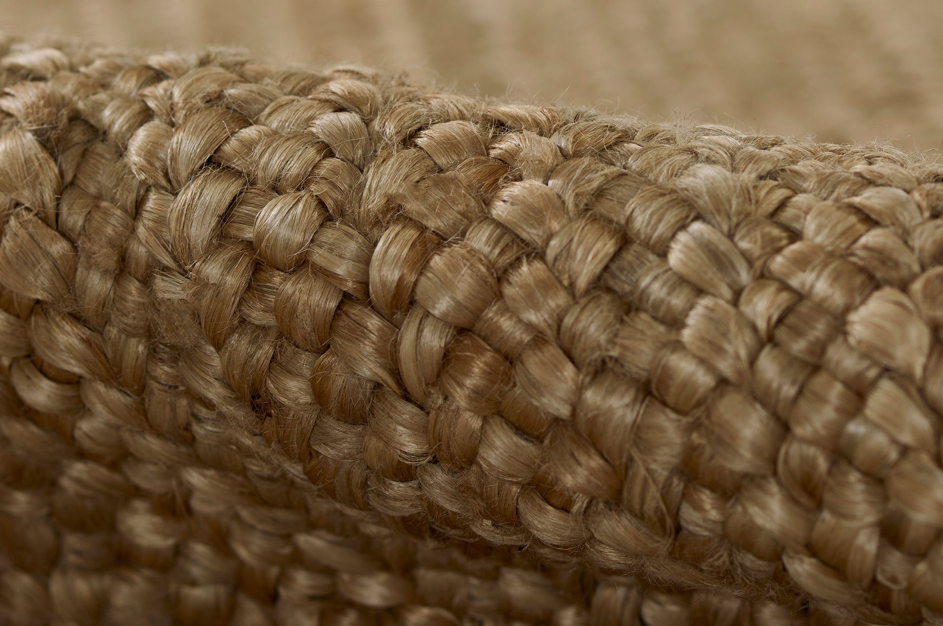 Natural tan braided jute texture, close-up on thick woven rope rug for rustic decor.
