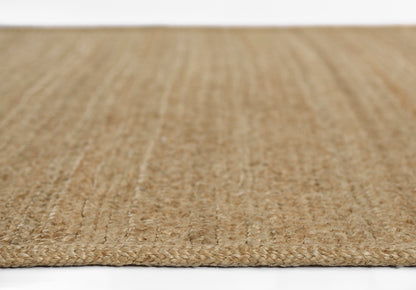 Natural beige jute rug close-up, flat-weave braided texture, rectangular shape, rustic coastal style.