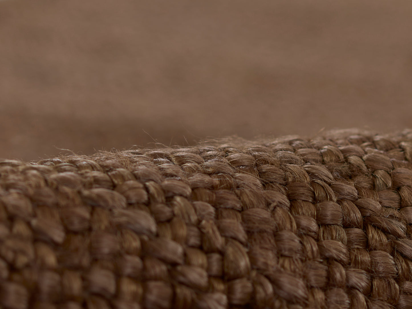 Close-up of warm brown braided jute fibers forming a textured rug.
