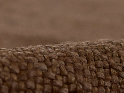 Close-up of natural brown braided jute fibers forming a rustic woven rug texture.