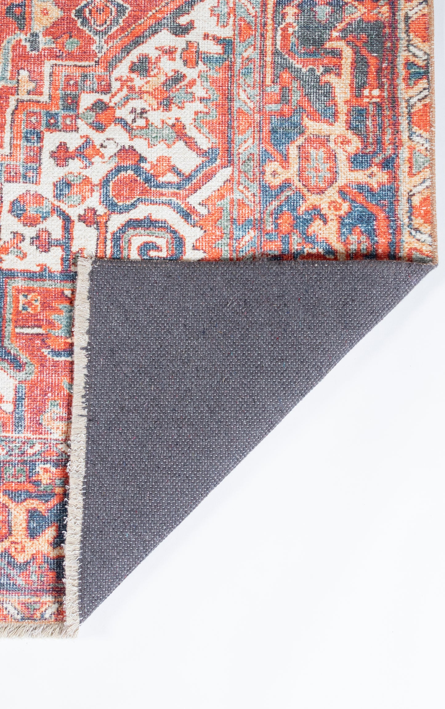 Red oriental rug with blue and ivory floral motifs; folded corner shows gray backing and fringe.