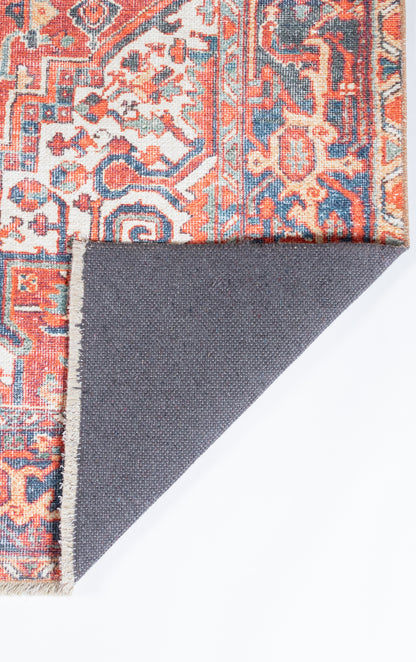 Oriental rug with red, blue & ivory floral motif; folded corner reveals gray fabric back.