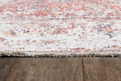 Red and ivory distressed patterned area rug with fringed edge on dark wooden floor