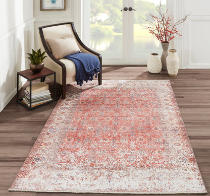 Red-toned Persian-style rug in a bright living room with beige upholstered chair, navy throw, side table & plant.
