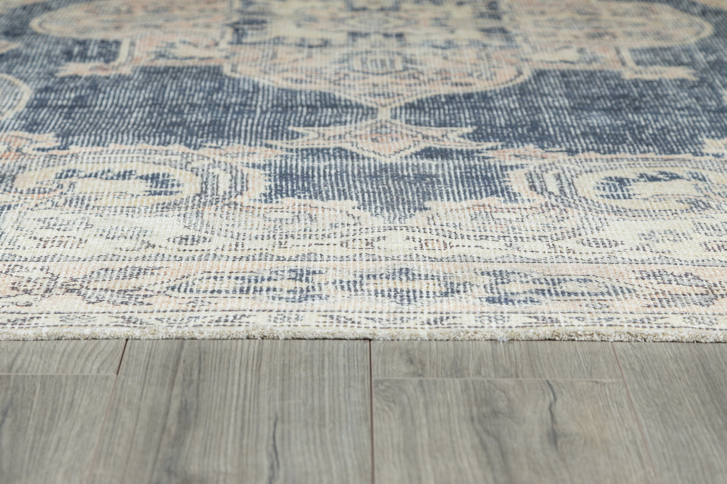 Navy blue, cream and beige oriental-style woven area rug with floral medallions on light wood floor.