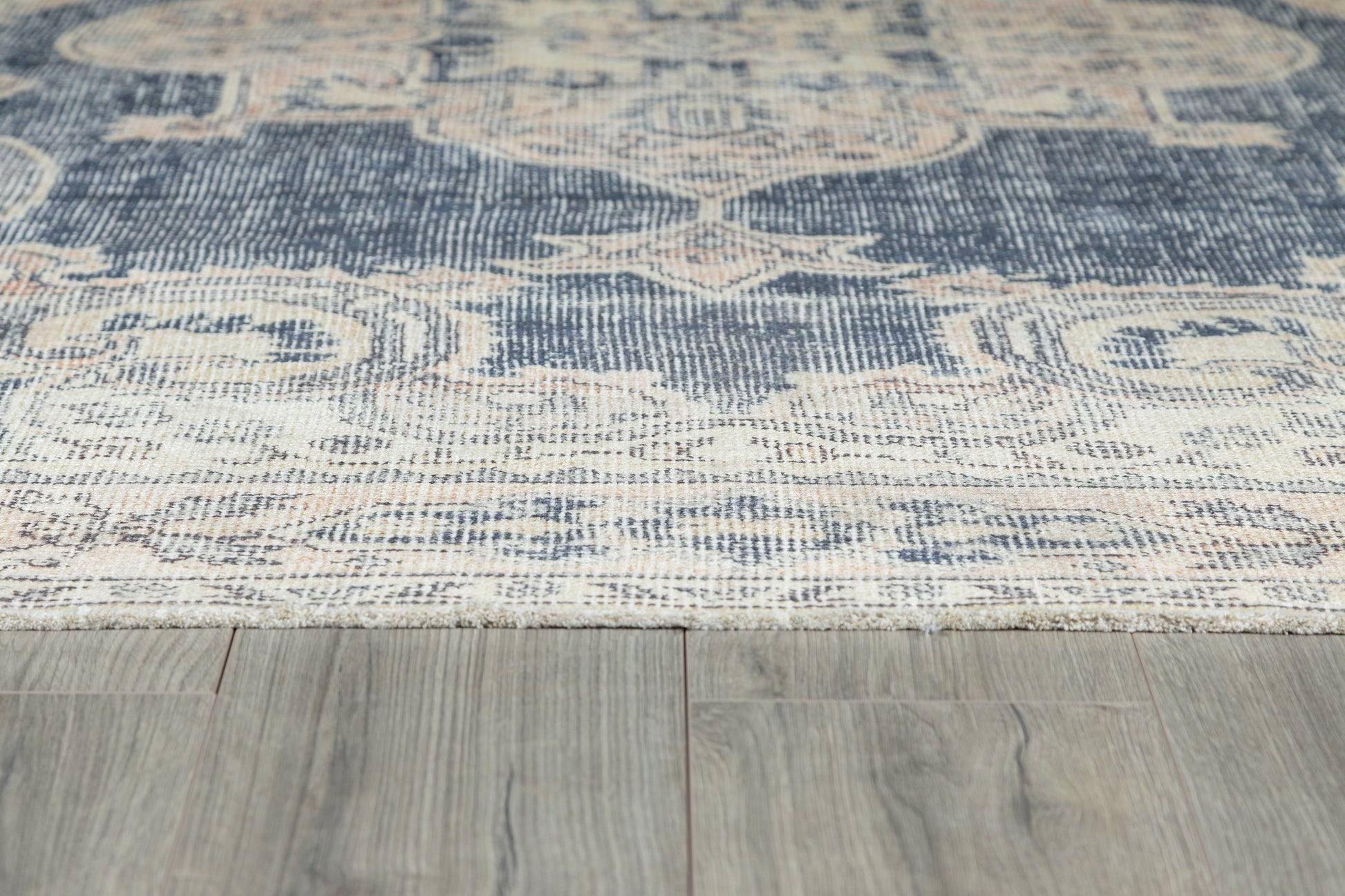 Navy blue, cream and beige oriental-style woven area rug with floral medallions on light wood floor.