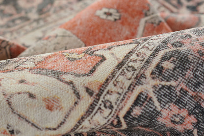 Close-up of an oriental rug with cream, orange-red and navy hues, featuring floral medallion motifs and a dense woven texture.