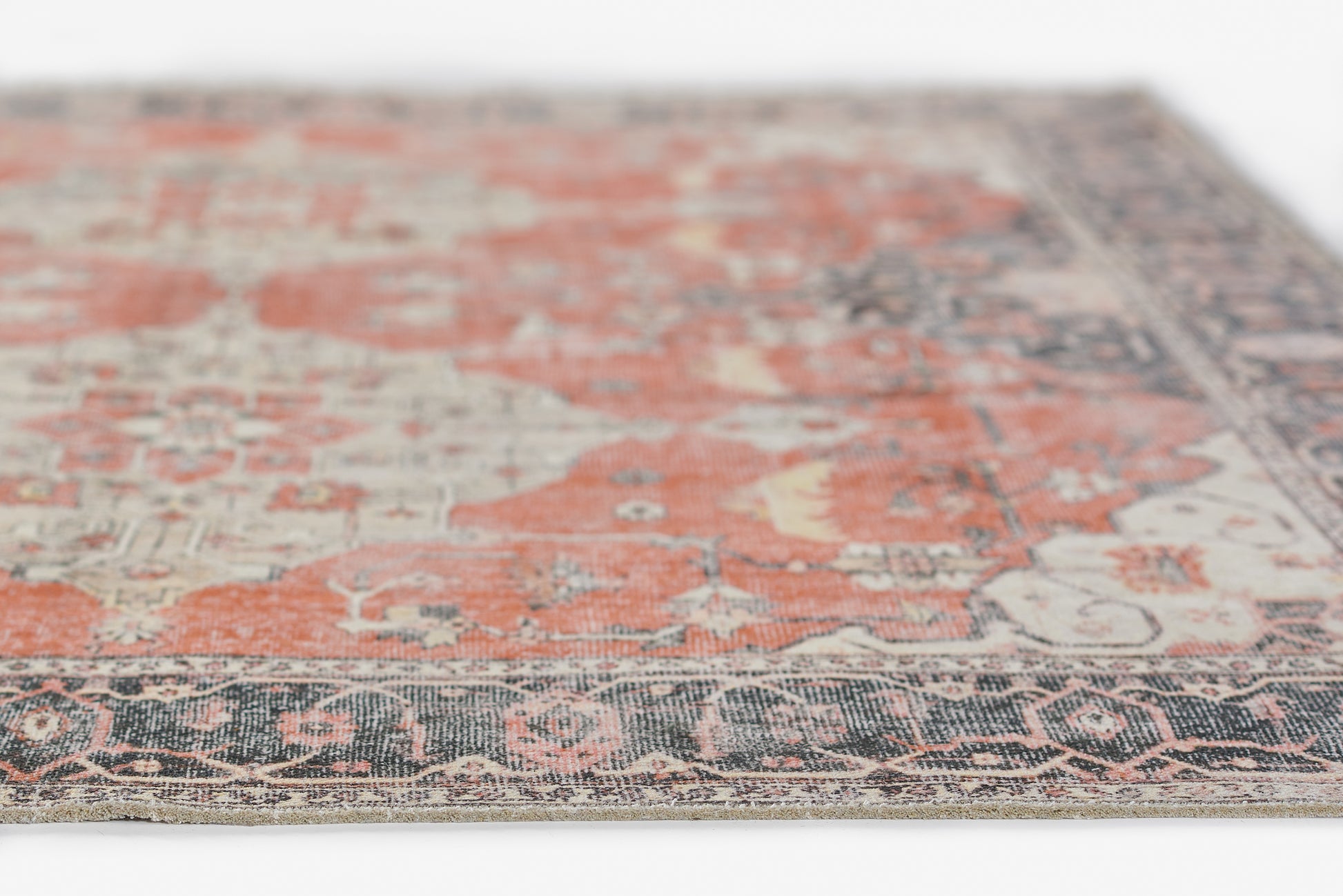 Persian-inspired rug with burnt orange and cream motifs, navy border, intricate floral pattern, angled close-up.