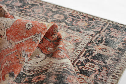 Wool rug in orange, cream and navy with a distressed Persian-style pattern and ornate bordered edges.