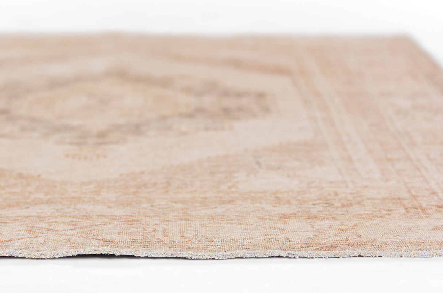Rectangular beige distressed flatweave rug with peach undertones and subtle geometric border.