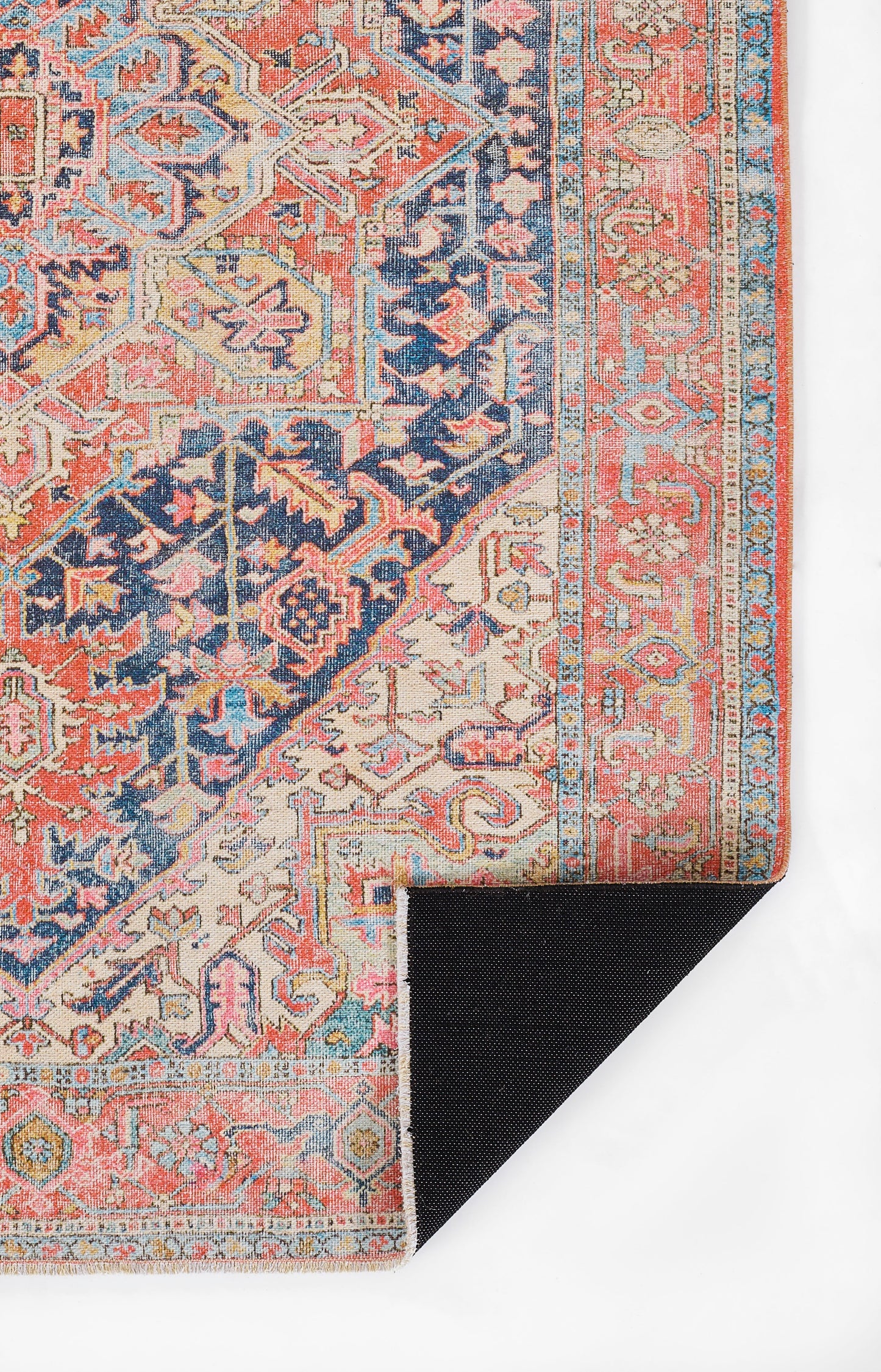 Colorful Persian-style oriental rug with coral, blue, ivory geometric motifs and floral border; corner shows navy back.