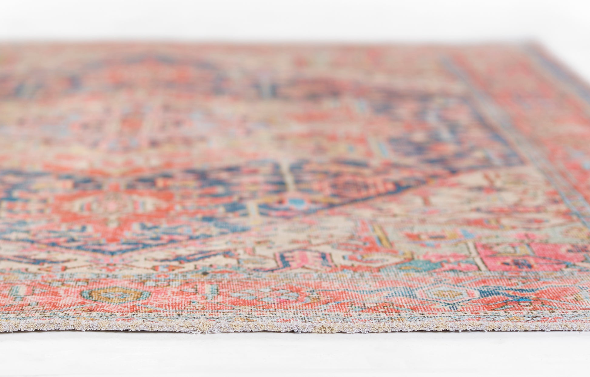 Close-up of a colorful oriental rug featuring red, blue and beige tones with intricate floral patterns.