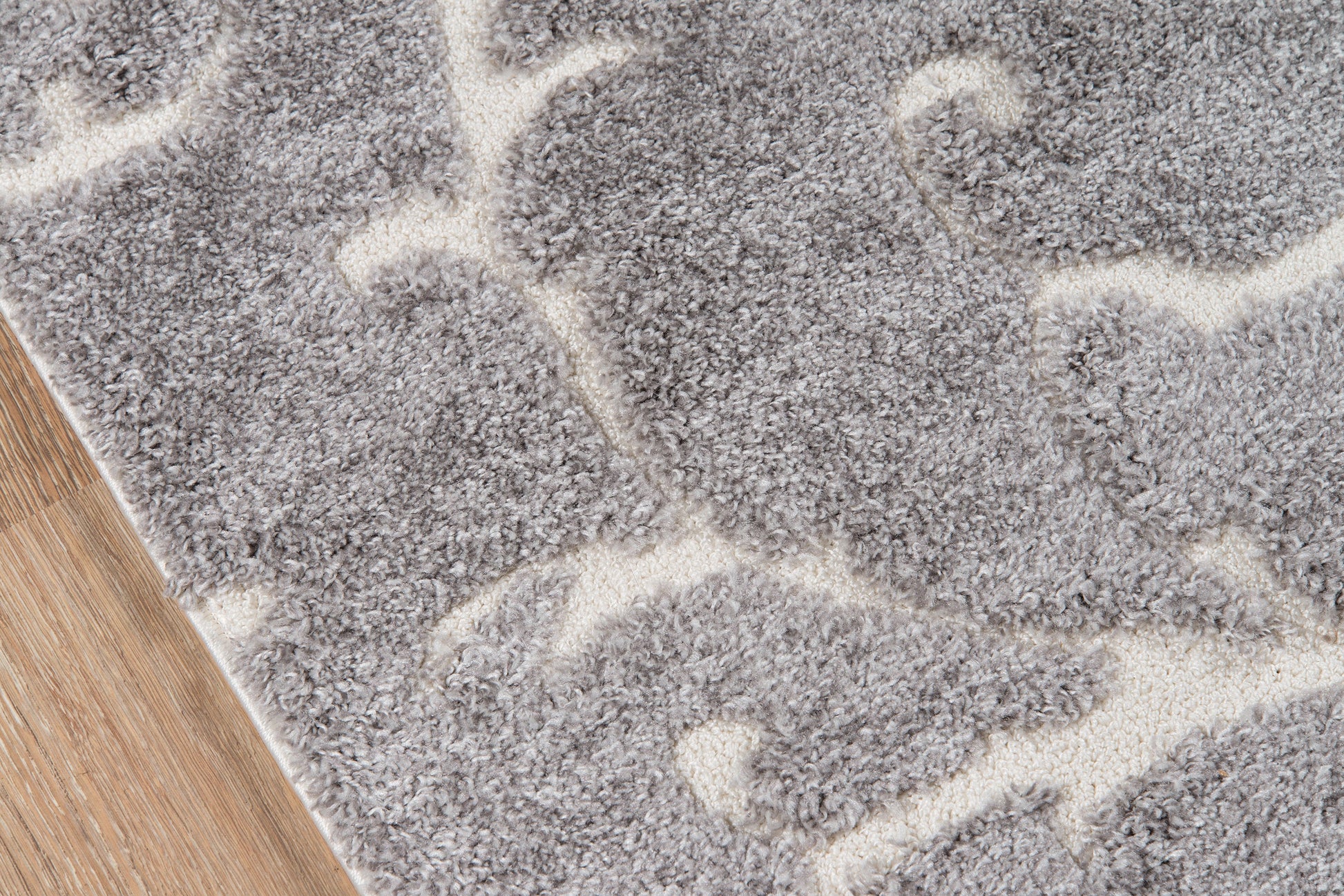 Gray shag rug with ivory abstract curved pattern on wood floor.