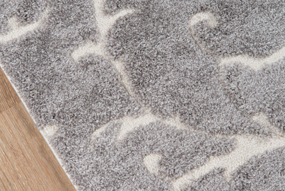 Gray shag rug with ivory abstract curved pattern on wood floor.