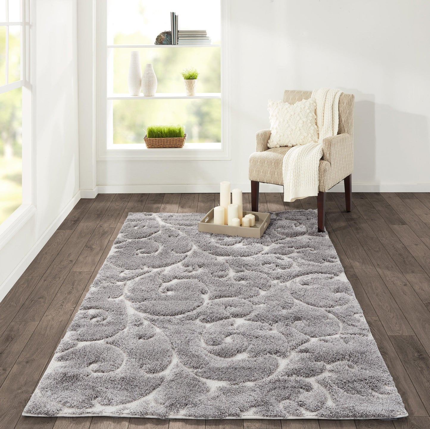 Rectangular gray shag area rug with a swirling pattern, placed in a bright living room beside a beige armchair.