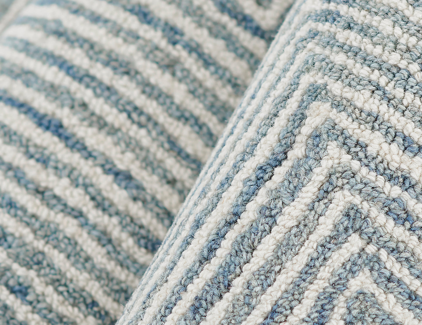 Close-up of a blue and white striped woven rug with a chunky loop pile and soft textured fibers.