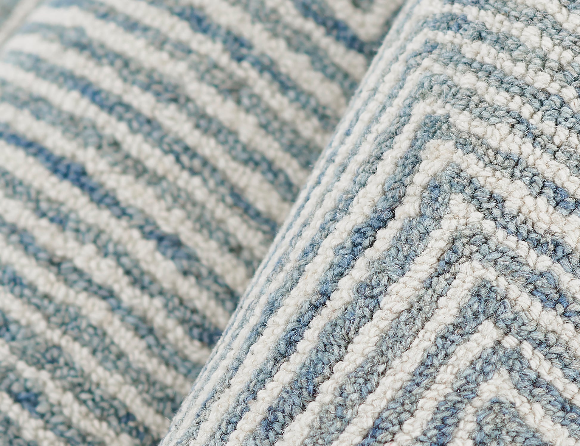 Close-up of a blue and white striped woven rug with a chunky loop pile and soft textured fibers.