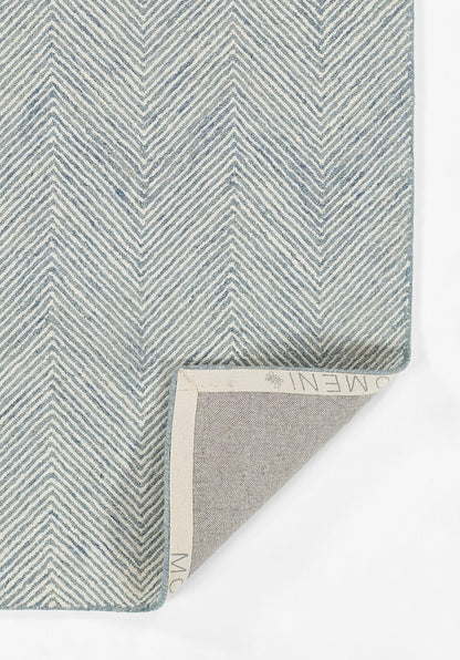 Blue chevron-pattern woven rug sample with light beige underside; folded corner reveals the backing.
