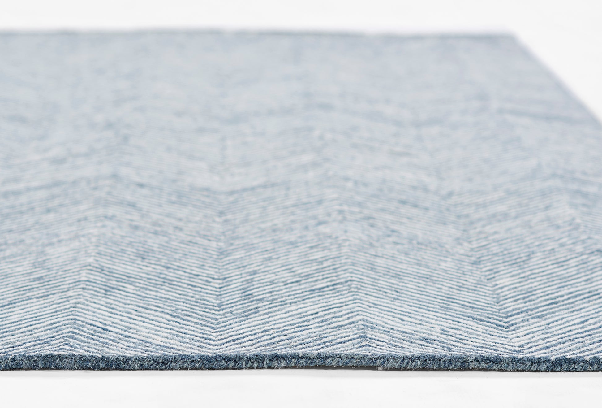 Blue-gray chevron patterned rug, white zigzag lines, flatwoven, rectangular, cozy home decor, edge bound.