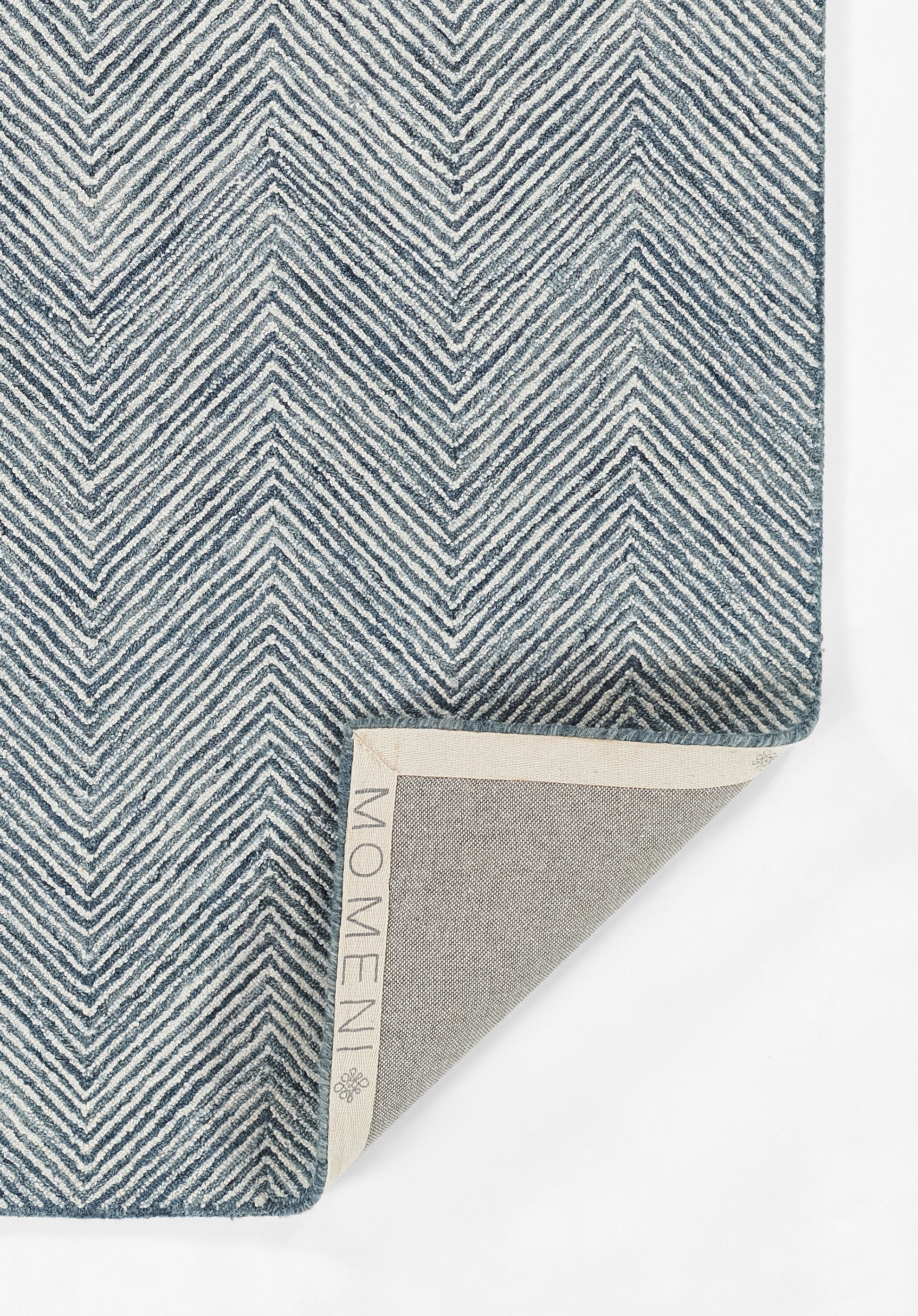 Blue and white chevron woven rug, folded corner shows beige backing with Momeni label.