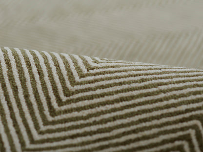 Close-up of olive green and white chevron woven rug with textured stripes, geometric decor.