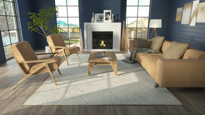 Contemporary living room with blue walls, tan leather chairs and sofa, wooden coffee table, gray rug, and fireplace.