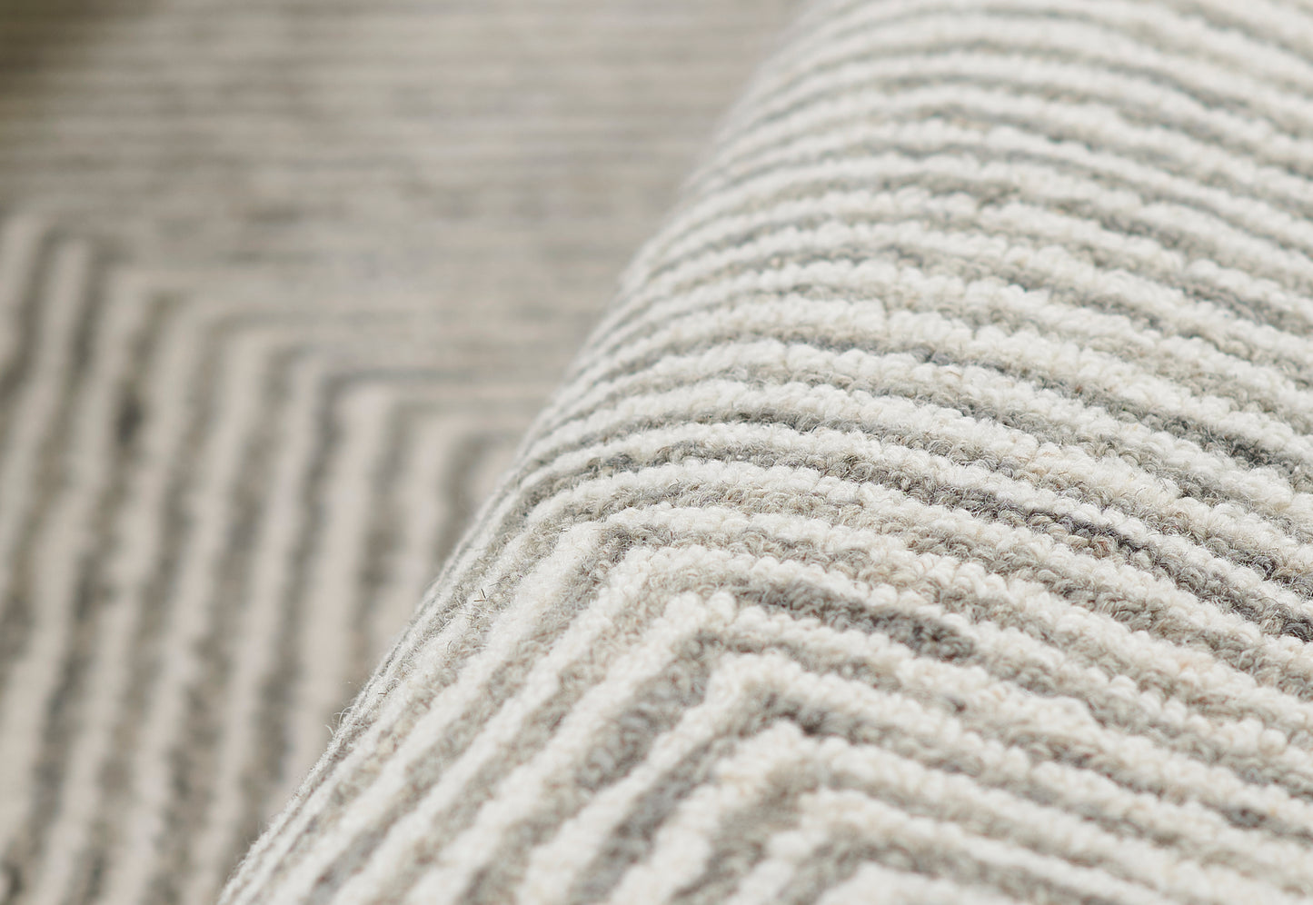 Charcoal gray rug close-up with plush ribbed loop pile, soft texture, rolled edge.