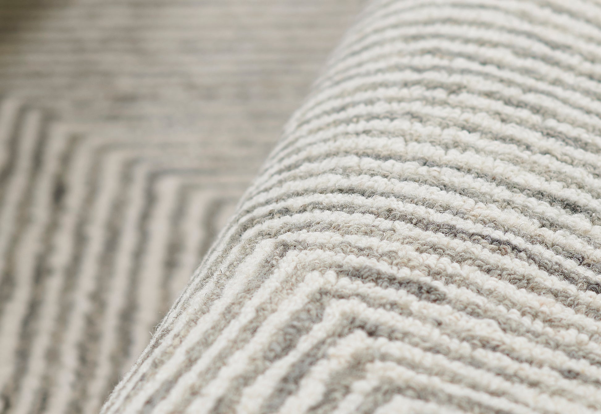 Charcoal gray rug close-up with plush ribbed loop pile, soft texture, rolled edge.
