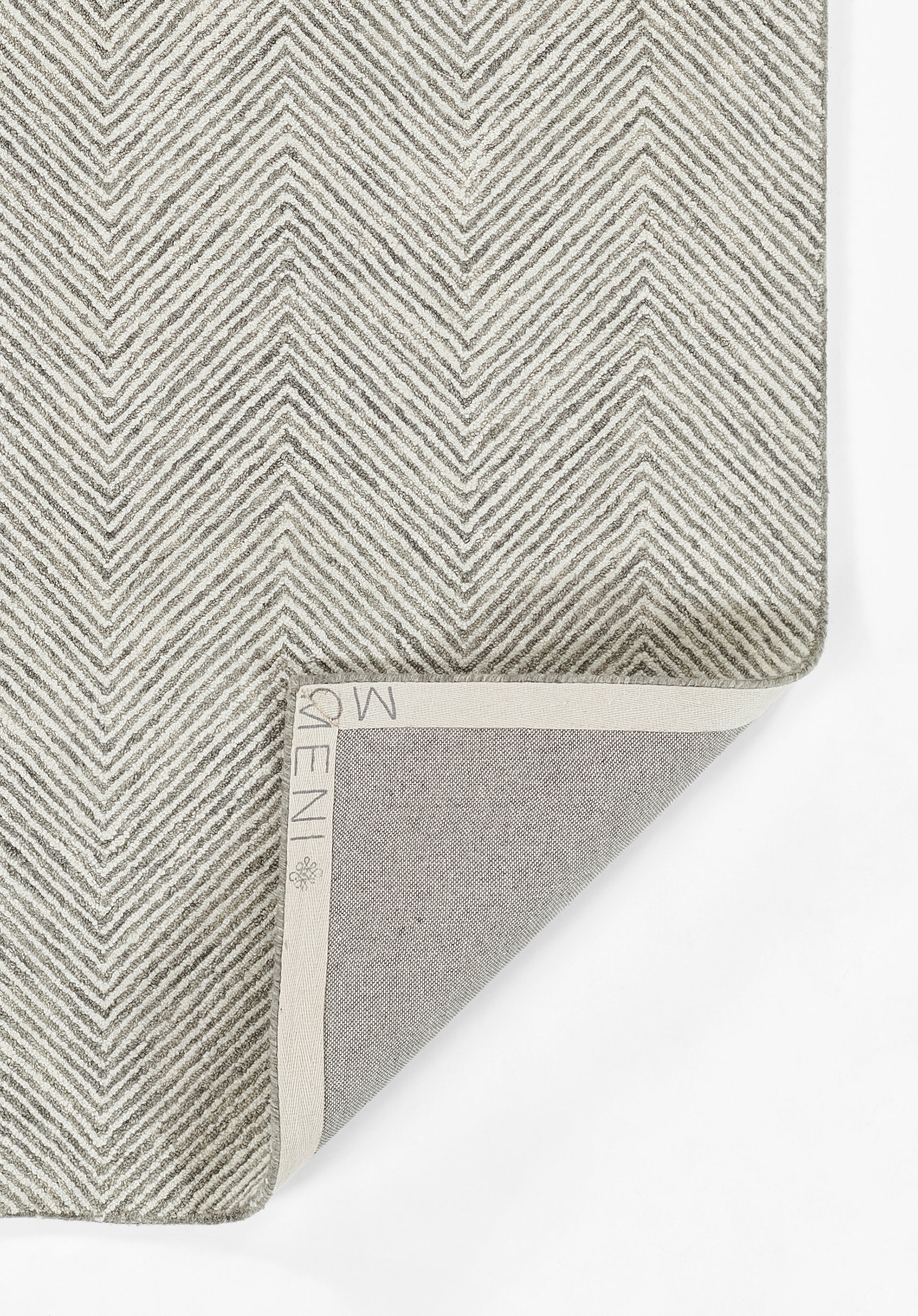 Gray chevron woven rug, with light cream binding; folded corner reveals gray underside and textured surface.