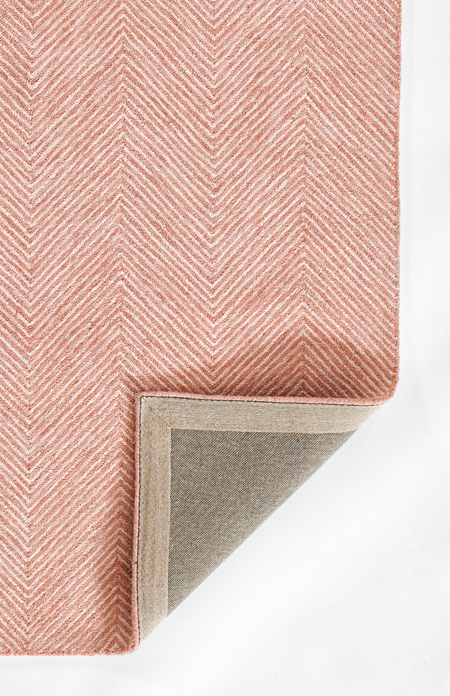 Pink chevron rug with soft pile; beige underside and grey backing shown at folded corner.