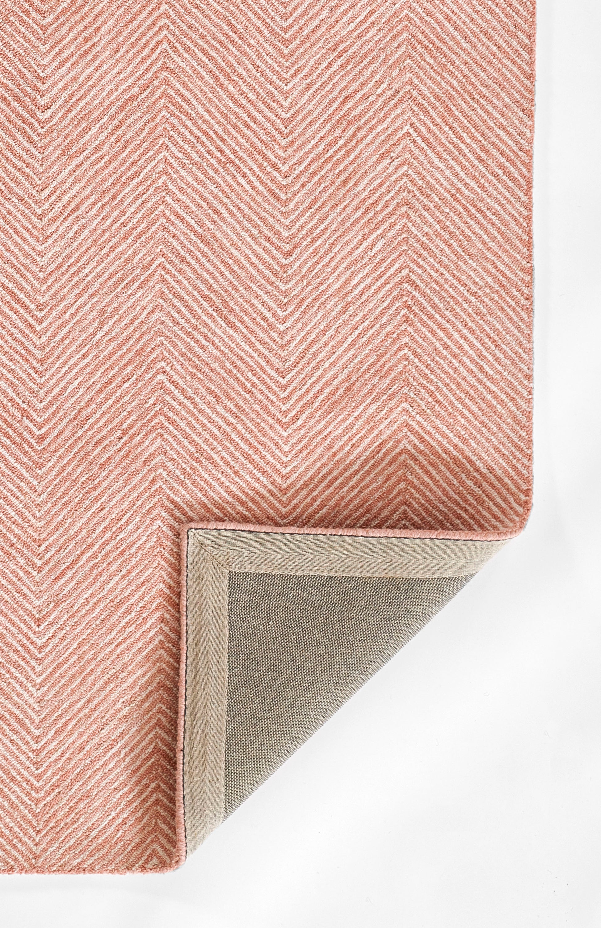 Pink chevron rug with soft pile; beige underside and grey backing shown at folded corner.