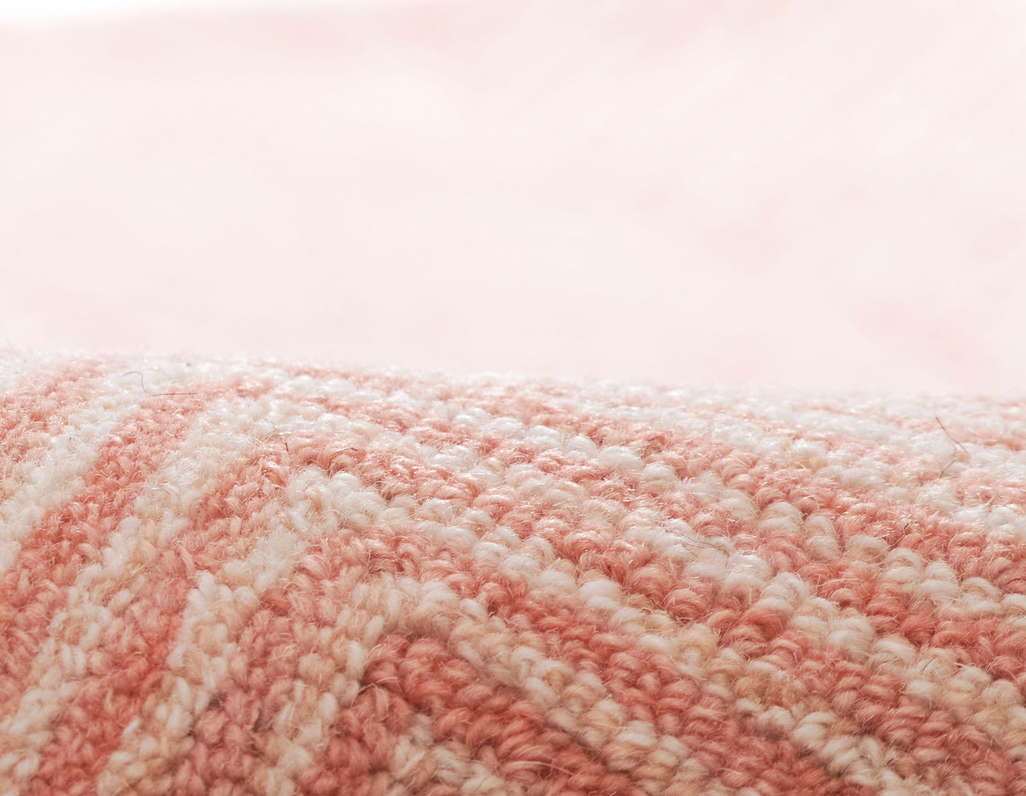 Close-up of a pink and white striped plush textile with looped yarn, rolled edge.