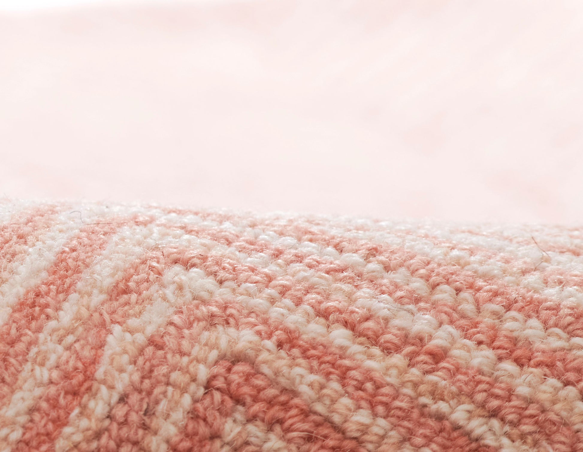 Close-up of a pink and white striped plush textile with looped yarn, rolled edge.