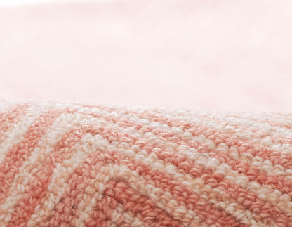 Close-up of a pink and white striped plush textile with looped yarn, rolled edge.